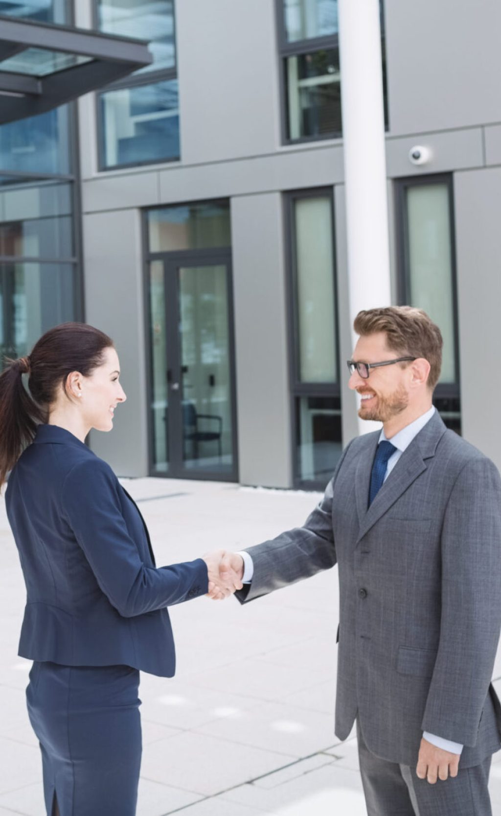 Businessman shaking hands with colleague outside office building
